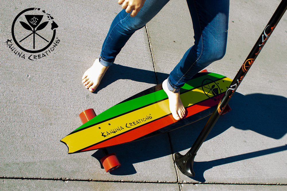 Woman standing on Kahuna Creations Haka Rasta longboard with land paddle.