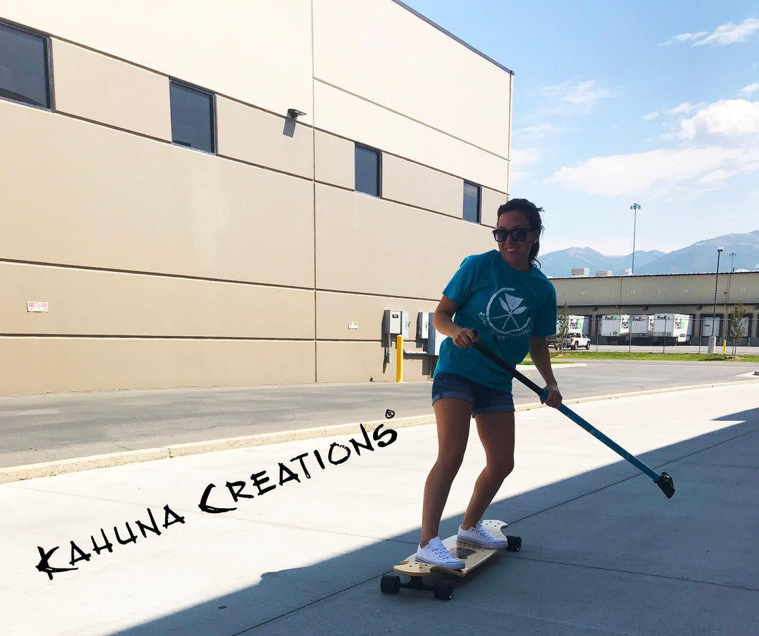 Woman riding Kahuna Creations drop deck longboard with land paddle.