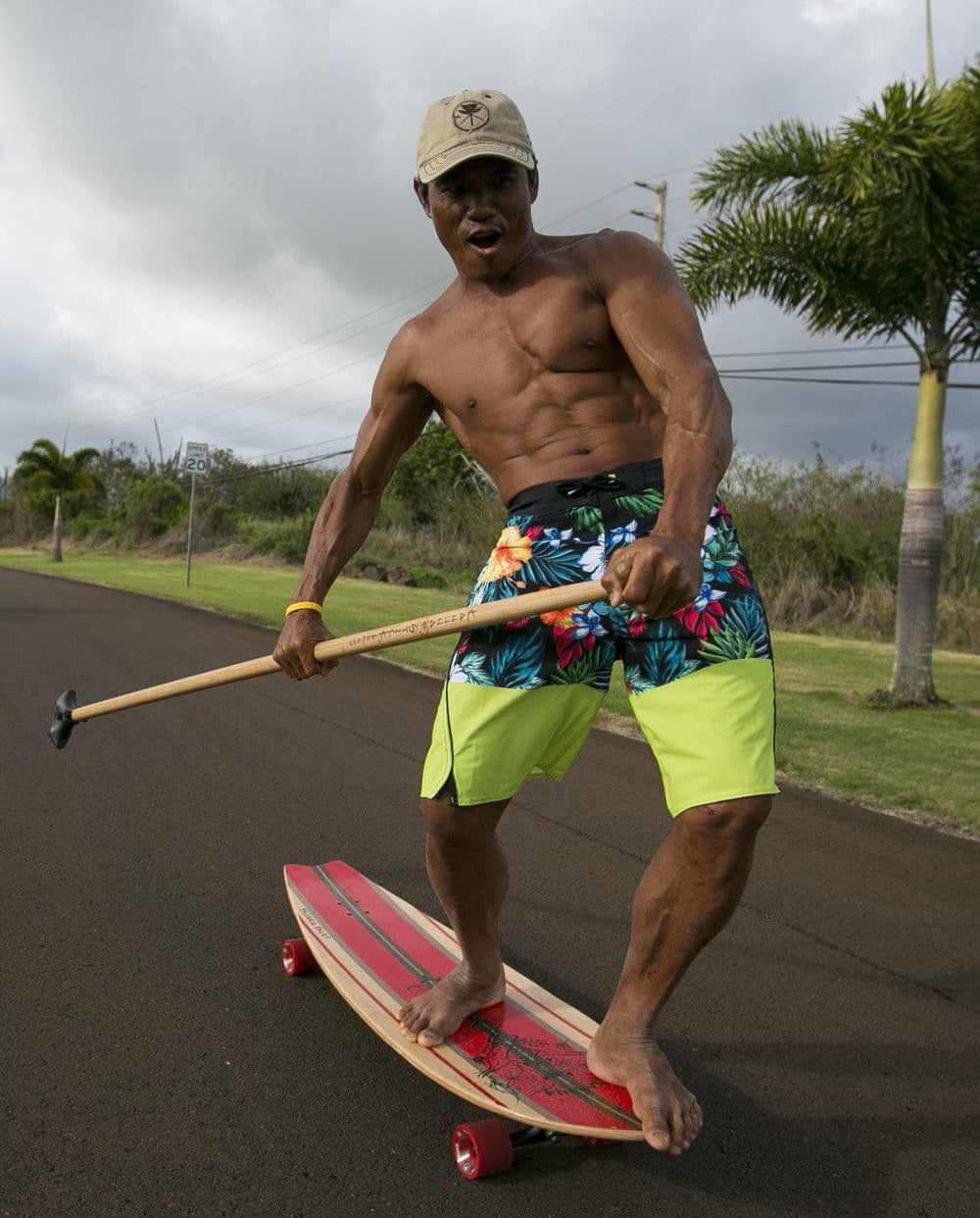 Man riding Kahuna Creations Shaka longboard with land paddle.