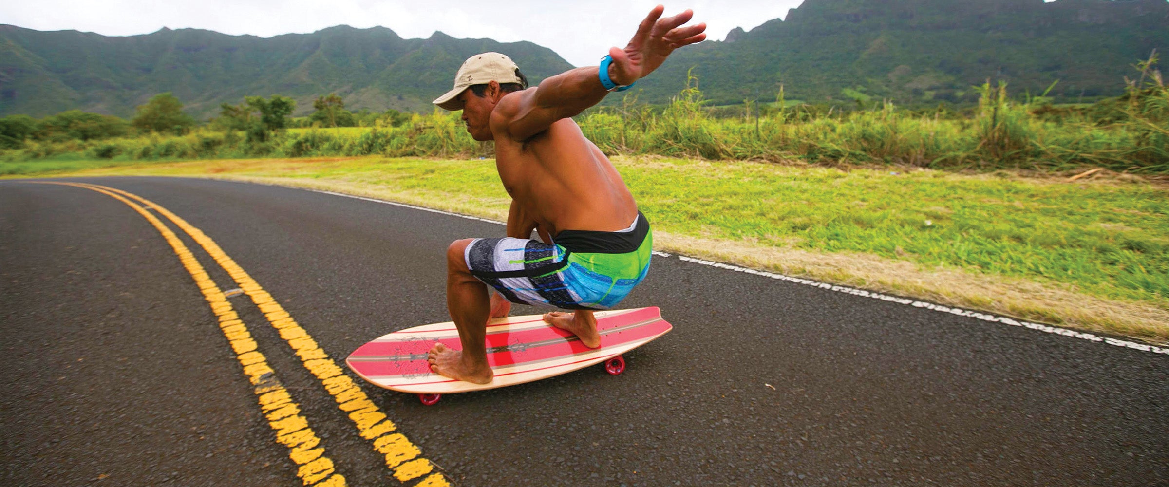 Man riding Kahuna Creations Shaka longboard skateboard with 180mm trucks, 69mm wheels and ABEC7 bearings in Hawaii.
