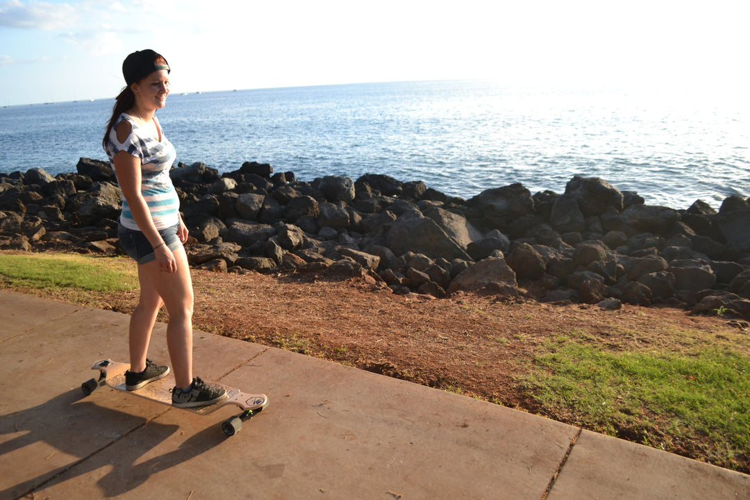 Woman riding Kahuna Creations drop deck longboard.