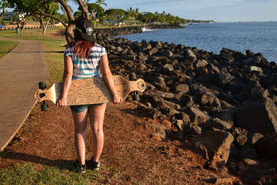 Woman holding Kahuna Creations drop deck longboard.