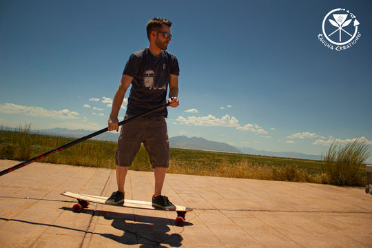 Man riding Kahuna Creations fishtail longboard with land paddle