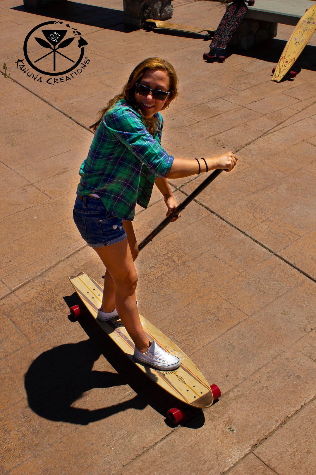 Woman riding Kahuna Creations fishtail longboard with land paddle