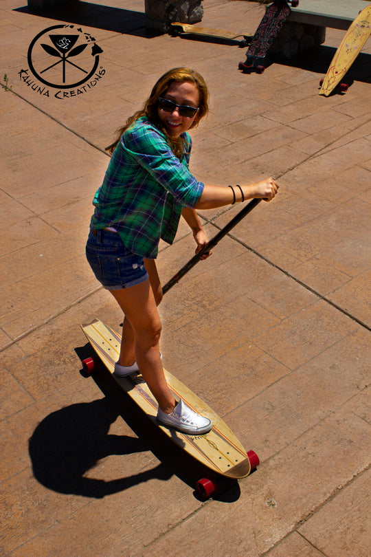 Woman riding Kahuna Creations fishtail longboard with land paddle