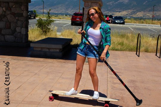 Woman riding Kahuna Creations fishtail longboard with land paddle