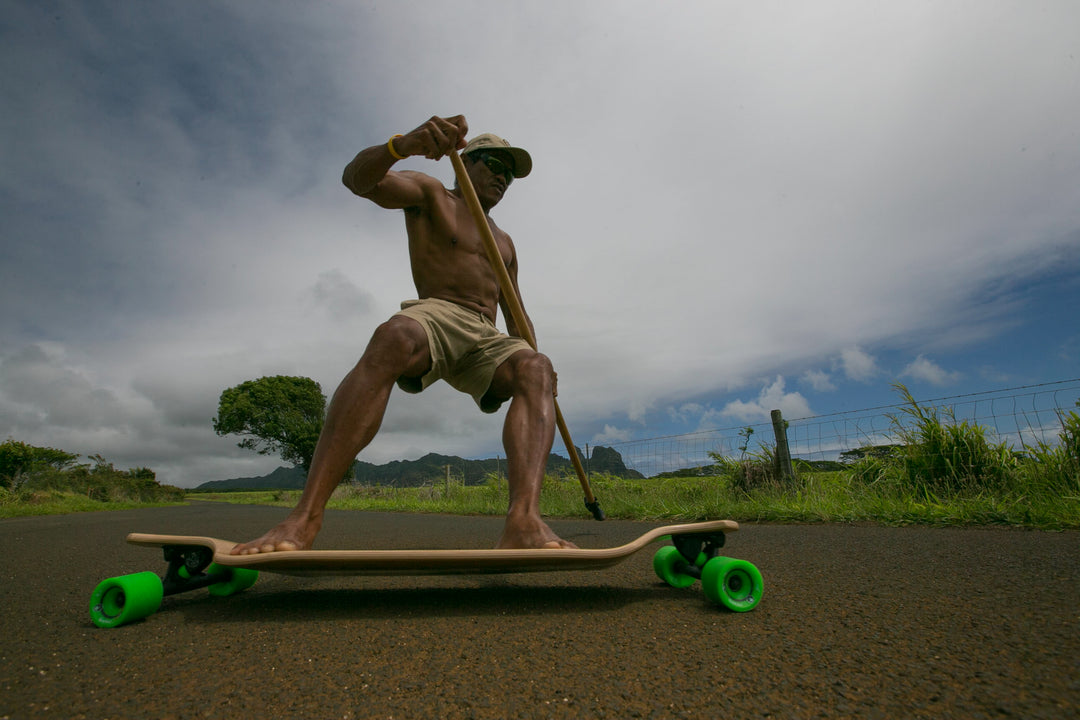 Man Using Kahuna Creations 42" Bamboo Drop Deck Longboard Skateboard and Land Paddle Hawaii